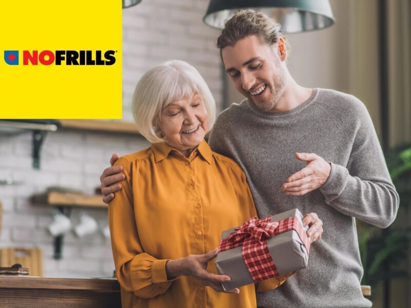 A young man is happily giving his mother a nicely wrapped gift. There's a yellow "No Frills" logo in the upper left corner.