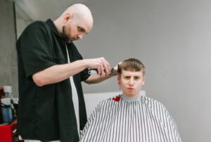 A man getting a haircut with an unhappy expression on his face while his right ear bleeds